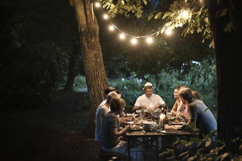 屋外の夕食のテーブルの上の庭の照明-友達