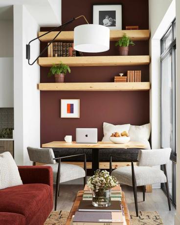 czerwone ściany, kącik śniadaniowy, drewniany stół, kremowe krzesła, pomarańczowa kanapa zaprojektowana przez byrona risdona