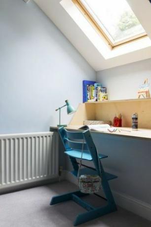 Sala de estudio para niños con silla azul, tragaluz y escritorio de madera
