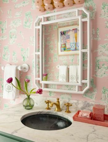 ein Waschbecken mit Spiegel und ein Regal mit Blumen