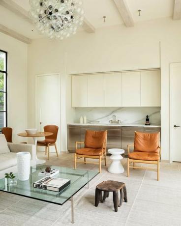 obývacia izba, hnedá kožená stolička, krémovo namaľované steny, biele drevené stropné trámy