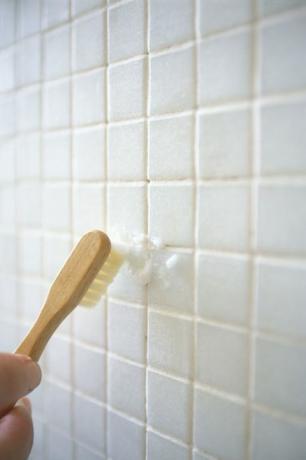Sikat gigi membersihkan dinding ubin kamar mandi