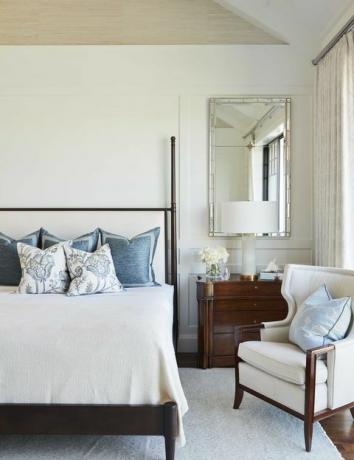 главная спальня, белый коврик с белым креслом, деревянный каркас кровати с постельным бельем и белое белье