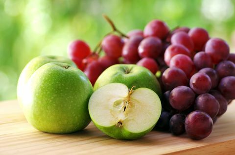 Maçãs e uvas na mesa de madeira