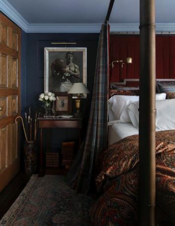 guļamistaba, zili krāsotas sienas, koka sānu galds, tartāna gultas aizkari