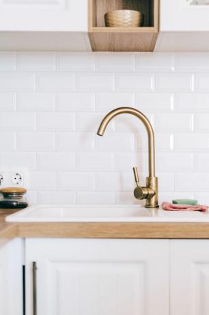 キッチンに金属製の洗面台が付いた金色の蛇口または水栓