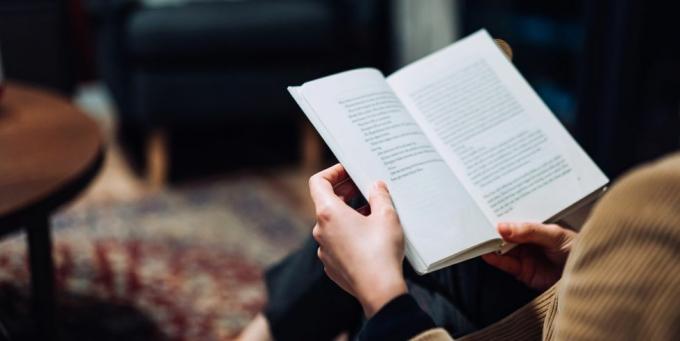 κομμένη φωτογραφία νεαρής Ασιάτισσας που κάνει ένα διάλειμμα από την τεχνολογία, χαλαρώνει και διαβάζει βιβλίο στον καναπέ σε ένα άνετο σπίτι το βράδυ