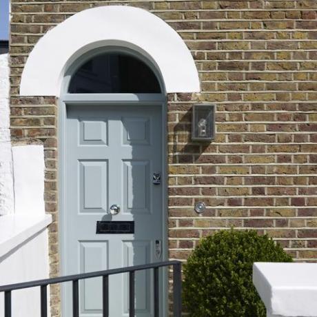 Puerta frontal azul pálido en casa de ladrillo