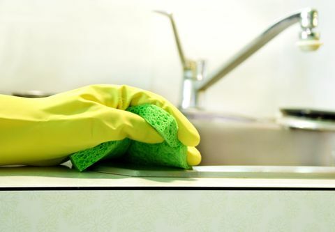 Gul handske som håller grön svamp
