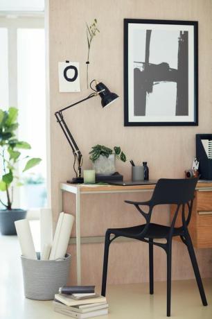 šviesi studija su stalu ir juoda kėdė