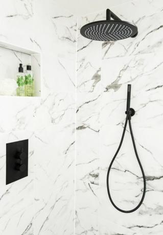 schwarzer duschkopf und armaturen auf einer wanddusche mit marmoreffekt