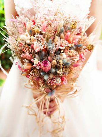 La sposa tiene in mano il suo mazzo di fiori secchi