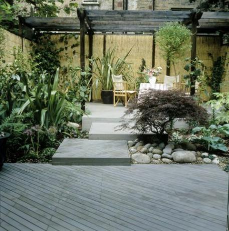 Terraza en el jardín de la ciudad, mesa y sillas bajo pérgola, biombo, acer entre guijarros duane paul design team