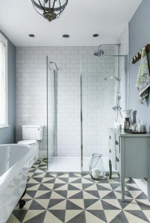 weiße freistehende Badewanne auf der linken Seite und eine begehbare DuscheDuschkabine mit einer einfachen, niedrigen Wanne für einen Feuchtraum-Look