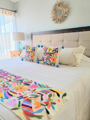 спалня, проектирана от soluna paz, разполага с отоми бродерия върху одеяло и чифт възглавници