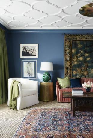 stue, blåmalt vegg, rød sofa, teksturert teppe og teppe