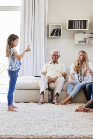 Familj med flera generationer som sitter på soffan hemma och spelar charader