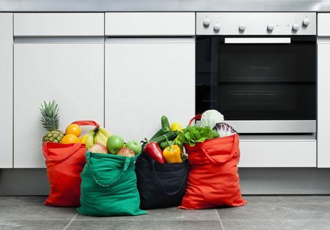 Opakovane použiteľné nákupné tašky naplnené ovocím a zeleninou v kuchyni.