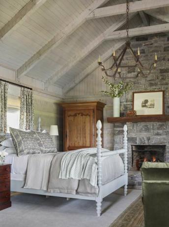 hálószoba, kő kandalló, fehér ágyrács, szürke ágynemű