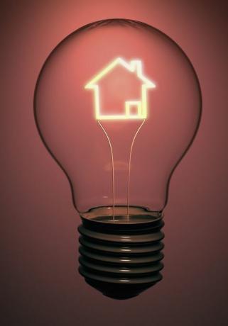 Bola lampu rumah tunggal berisi filamen bercahaya dalam bentuk rumah yang menunjukkan energi, listrik, dan masalah hijau