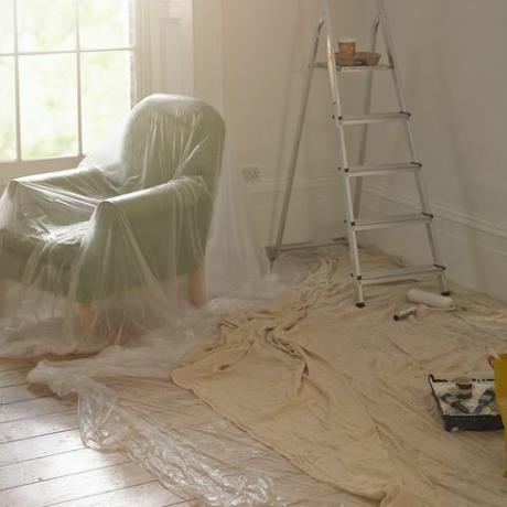 sebuah ruangan dengan seprai debu, tangga, dan roller cat