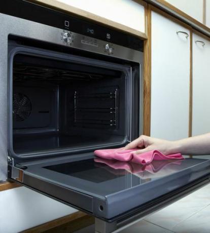 Frauen putzen den Ofen mit Handtuch