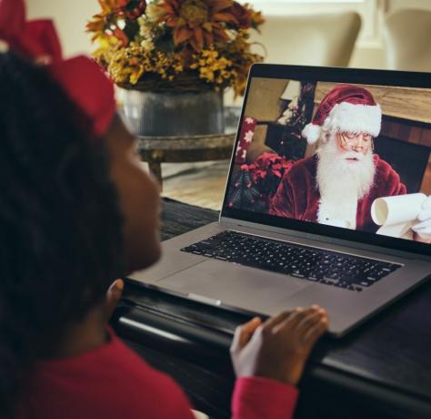 Ein kleines Mädchen, das mit dem Weihnachtsmann bei einer Computer-Videokonferenz spricht