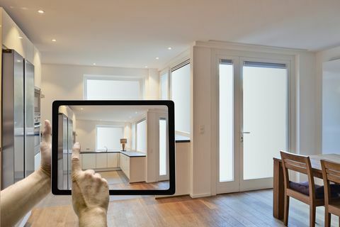 Dispositivo móvil con manos de hombre tomando fotografías en la cocina moderna renovada