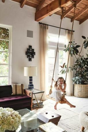 Una niña se balancea en un columpio interior en una sala de estar formal