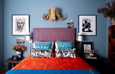 makuuhuoneessa siniset seinät ja oranssit vuodevaatteet