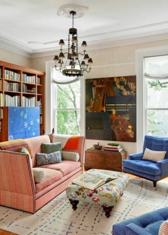 キャスリーンウォルシュのリビングルーム、ピンクのソファ、青い椅子、クリーム色の壁、花柄のオットマン