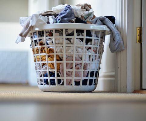 床の白い洗濯かごの中の服の山