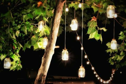 Upplysta dekorationer som hänger från ett träd i en trädgård på natten