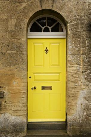Φωτεινή κίτρινη μπροστινή πόρτα σε πέτρινο σπίτι