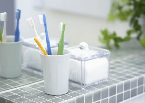 Escovas de dentes em um porta-escovas com esponja de algodão em um banheiro.