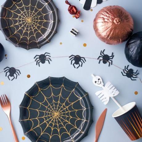 Piring Pesta Halloween dihiasi dengan jaring laba-laba yang dihiasi dengan kertas tembaga mengkilap.