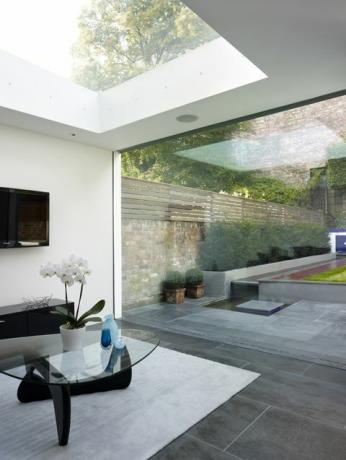 Salón moderno con tragaluz y pared abierta con vistas al jardín de Walham Grove, Reino Unido