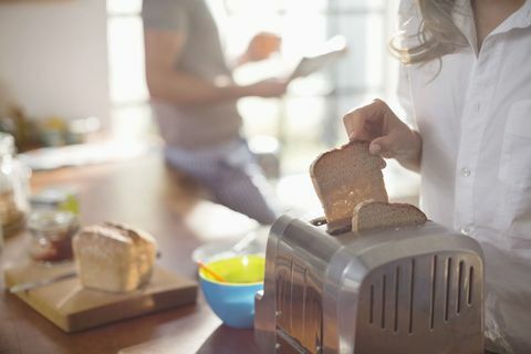 Frau legt Brot in den Toaster