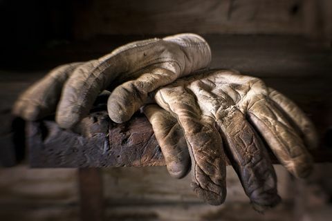 古い作業台の上にある、よく着用された汚れた油性の作業用手袋。