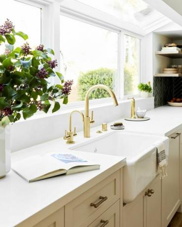 Waschbecken mit goldenem Wasserhahn, cremefarbene Schränke mit cremefarbener Marmorplatte