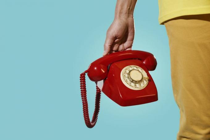 muž so starým červeným telefónom v ruke