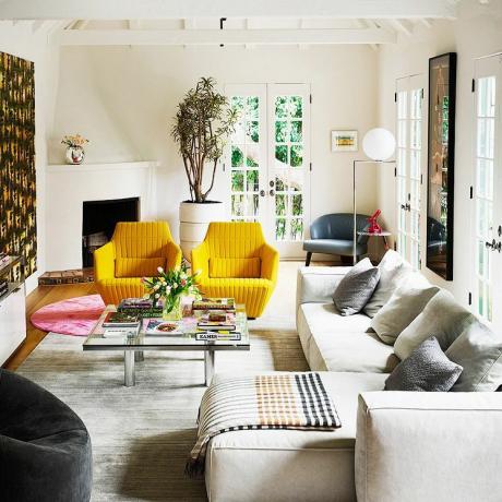 veľká biela obývačka so žltými stoličkami a prierezom