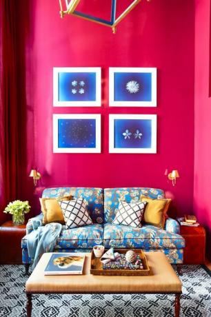 ห้องนั่งเล่นสีชมพูร้อนพร้อมโซฟาสีน้ำเงินและงานศิลปะ