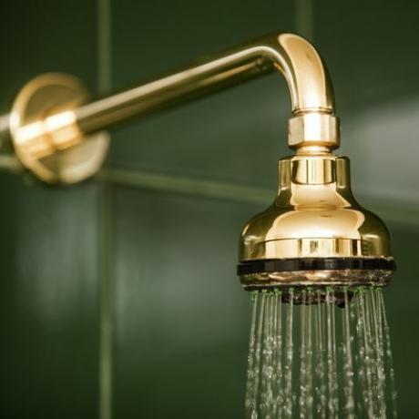 Metallic-Gold-Badezimmer-Duschkopf und fließendes Wasser