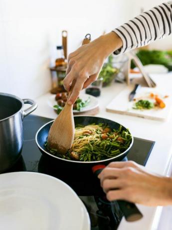 Mladá žena vaří veganské těstoviny ve své kuchyni
