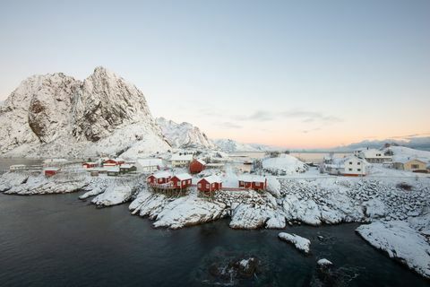 Црвено рибарско село међу снегом са погледом на планине на острву Лофотен Хамнои, Норвешка