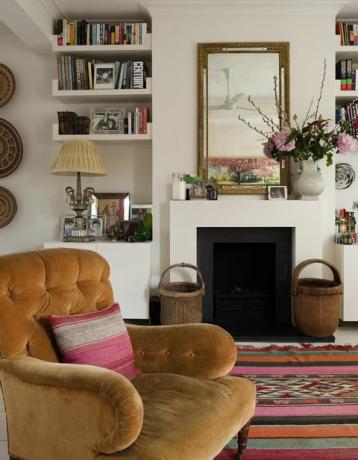 brūns pogāms atzveltnes krēsls no Džordža Smita baltā viesistabā ar marokāņu paklāju un kamīnu, interjera dizaineres Sāras Vanrenenas dzīvoklis Londonā