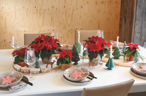 Kalėdinio stalo centre esantis miniatiūrinis medinis traukinių komplektas