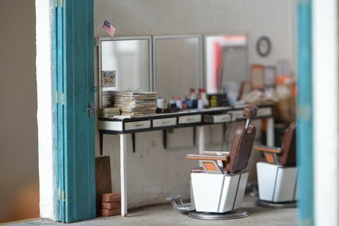 miniaturowa replika salonu fryzjerskiego z trzema lustrami, dwoma krzesłami fryzjerskimi i ladami zawierającymi artykuły fryzjerskie