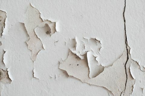 біла фарба тріскається і відшаровується від стіни